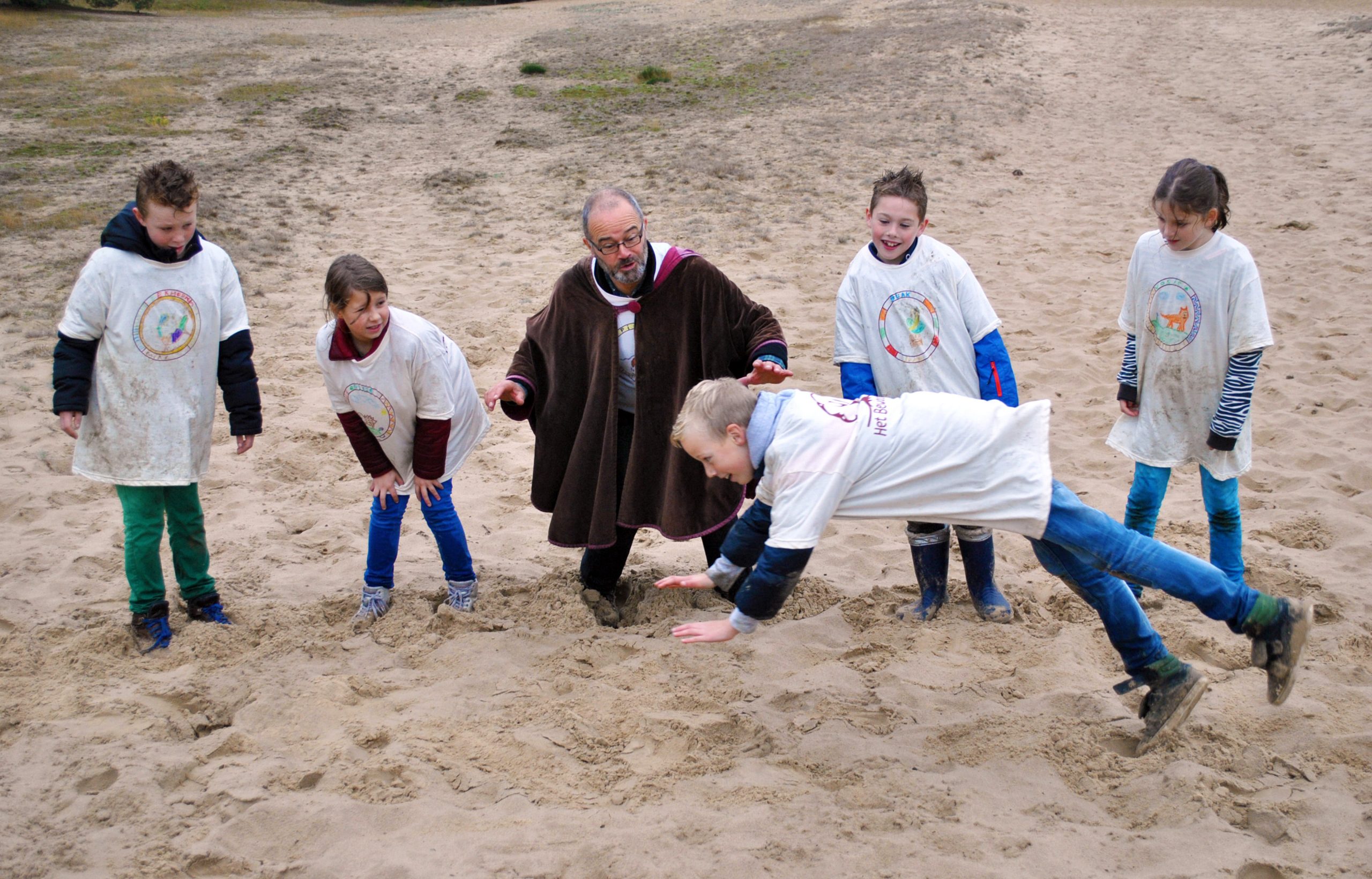 Kinderen springen in het zand van de Loonse en Drunense Duinen tijdens Het Bewaarde Land