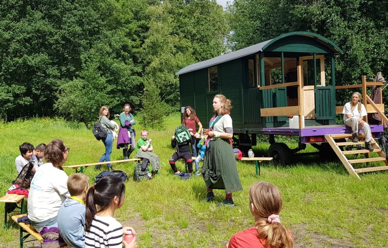 Kinderen luisteren naar vrouw Fleur in Het Bewaarde Land in Tilburg / Stadsbos013