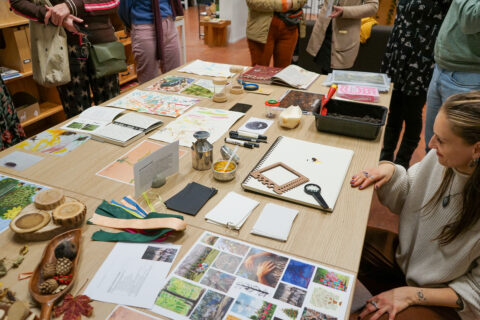 Een groep mensen verzamelt zich rond een tafel met creatieve en natuurgerelateerde materialen.