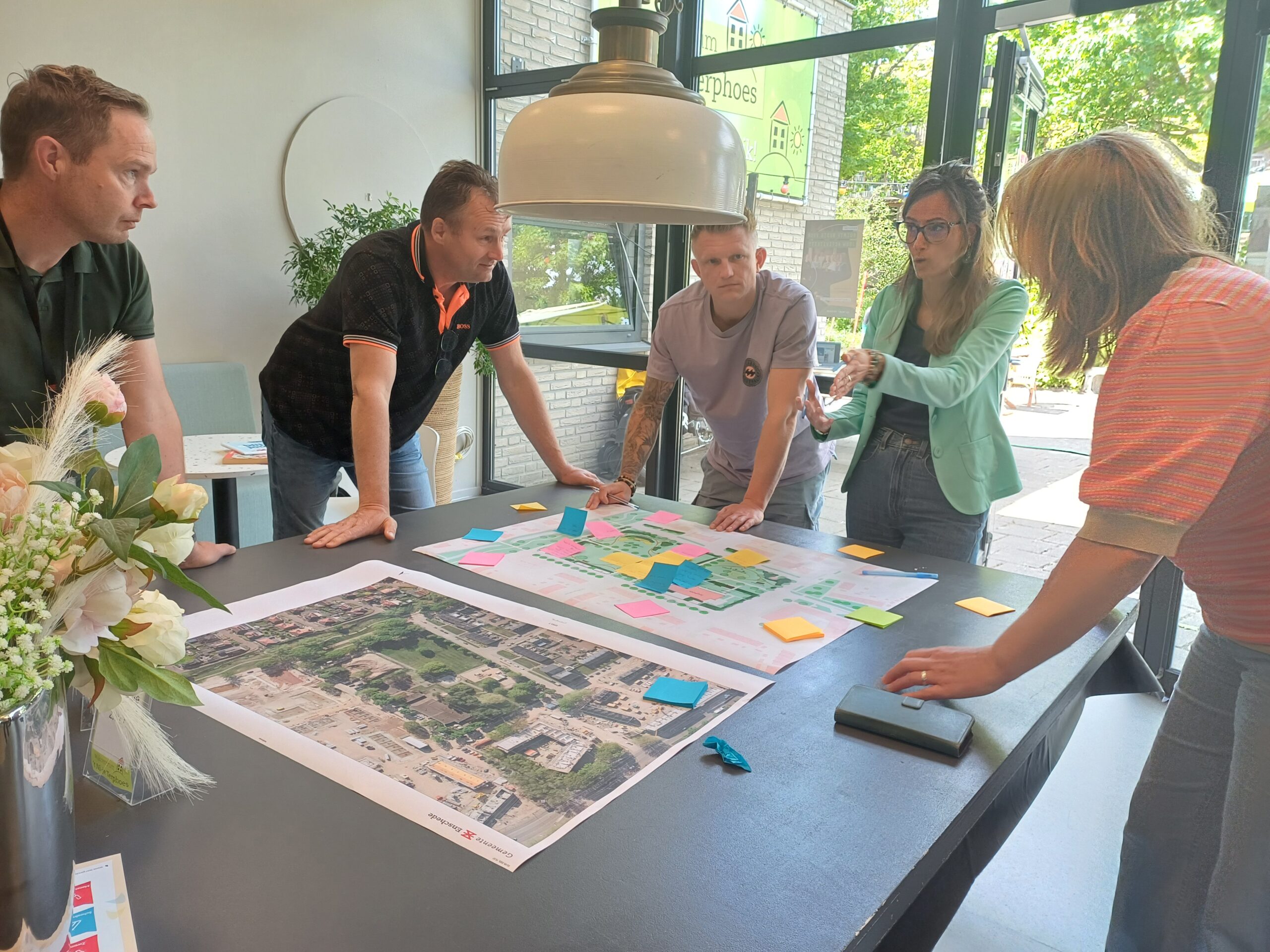 Mensen overleggen rond een tafel met een kaart en gekleurde notities in een lichte ruimte.