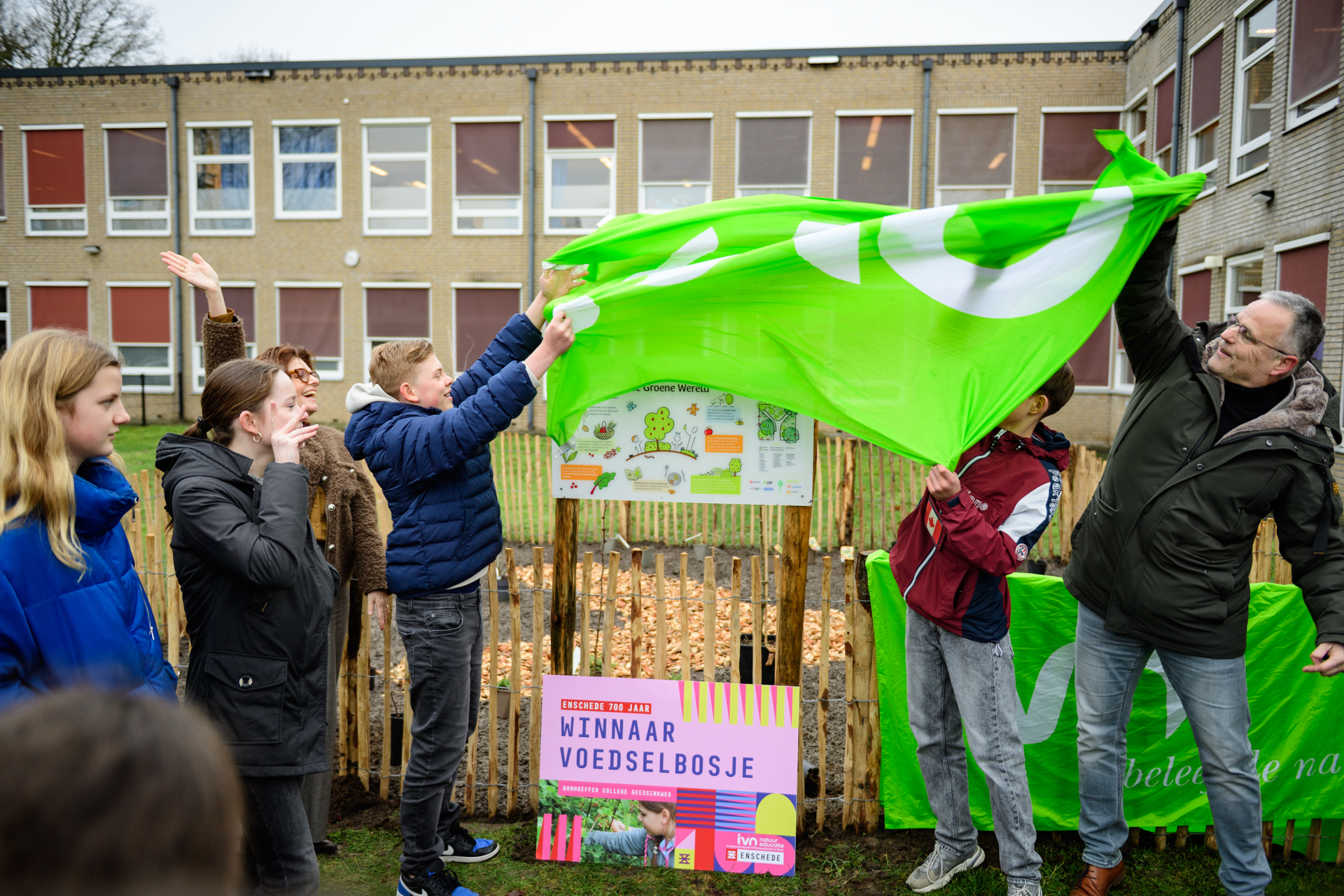 Mensen onthullen een bord voor een "Voedselbos" bij een gebouw tijdens een ceremonie.