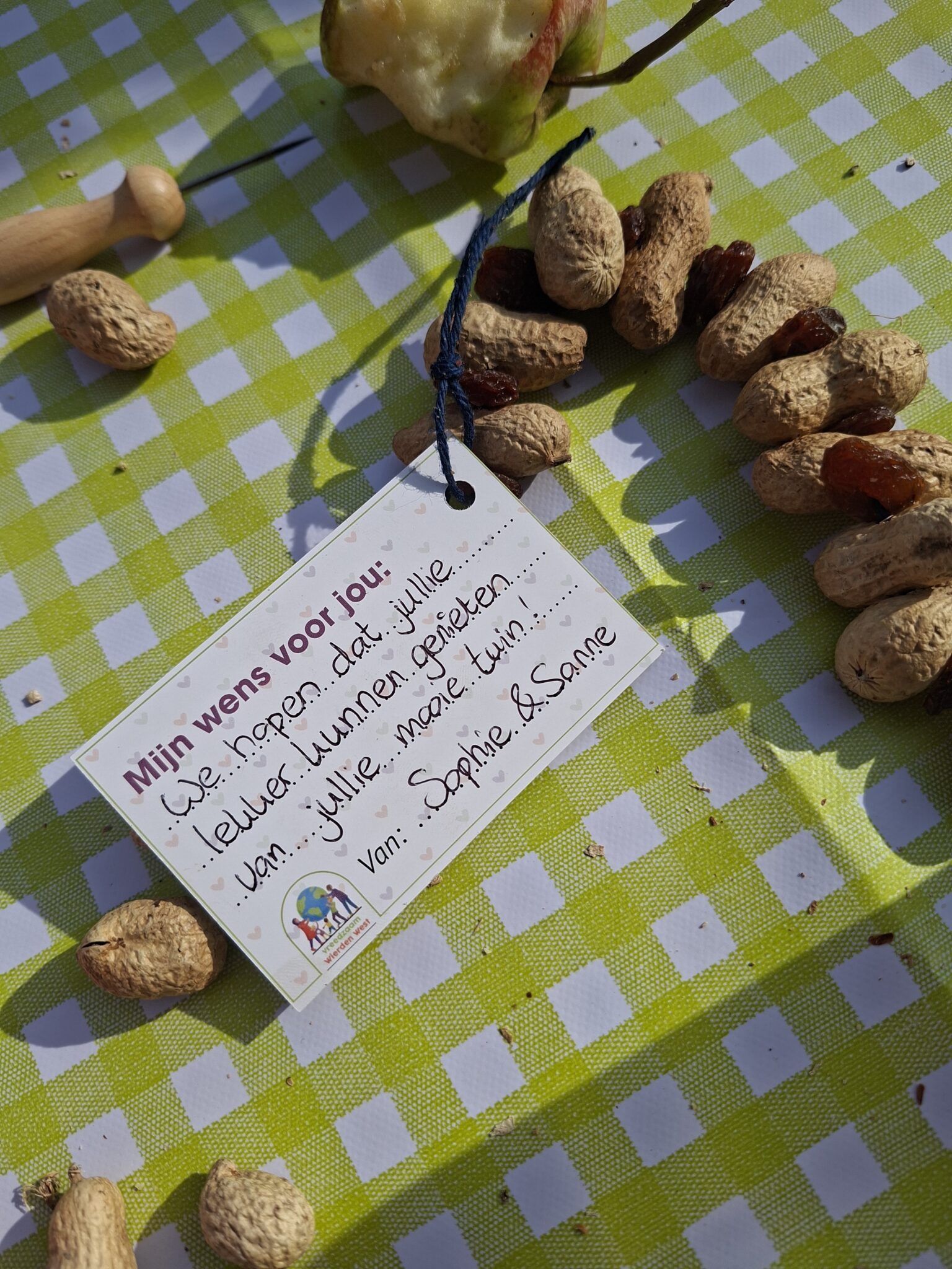 Wenslabel met pinda's en krenten op groen-wit geruit tafelkleed.