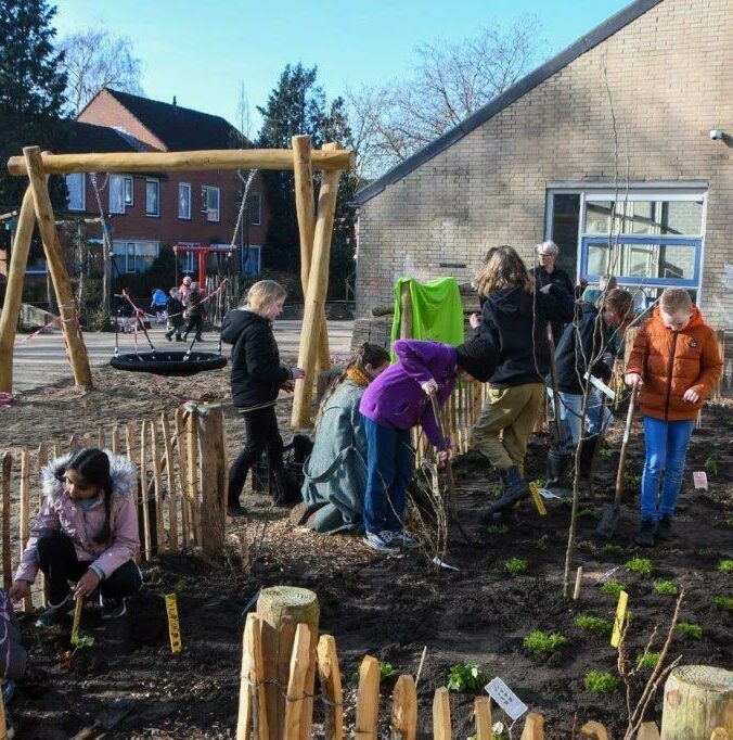 Kinderen planten bomen in een tuin naast een schoolgebouw.