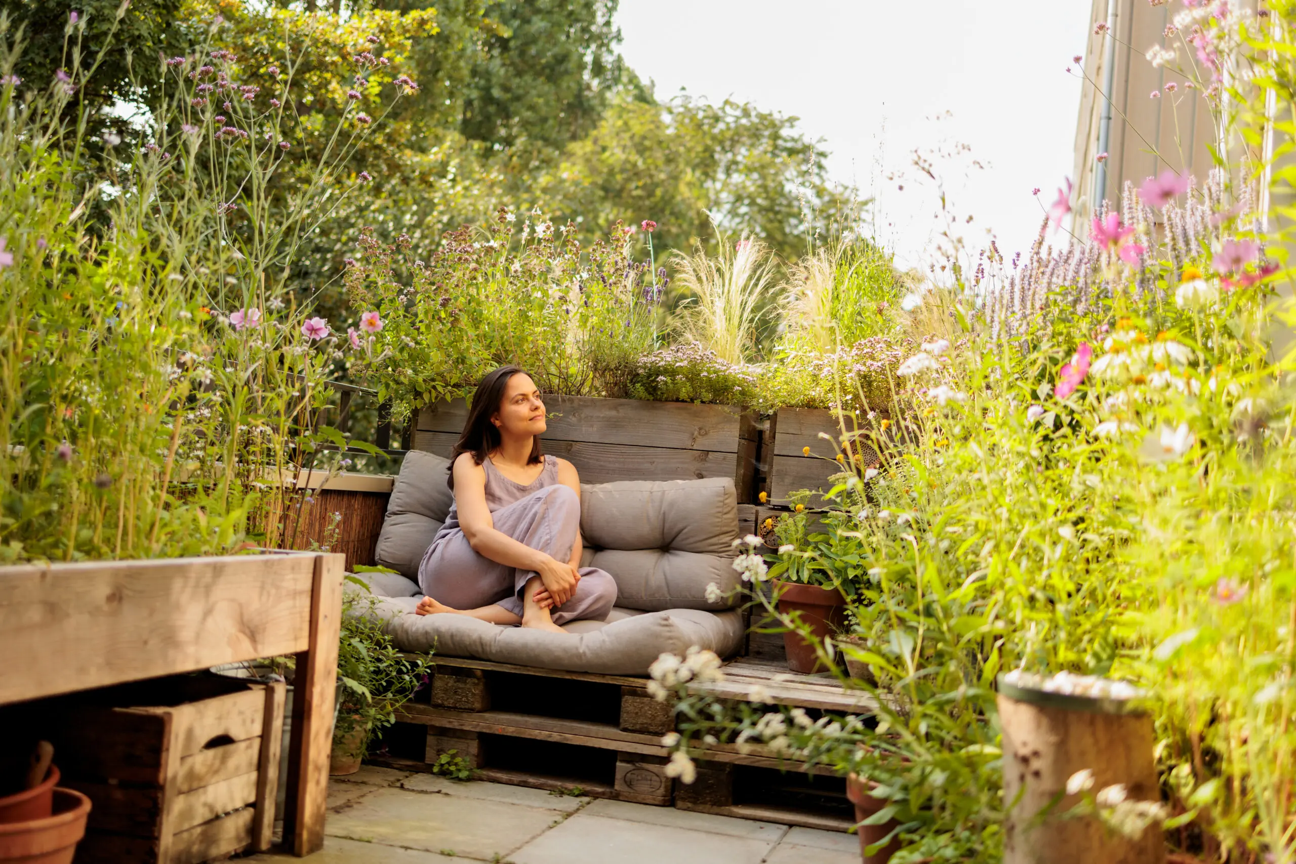 Vrouw ontspant op een bank in een weelderige, zonovergoten tuin.