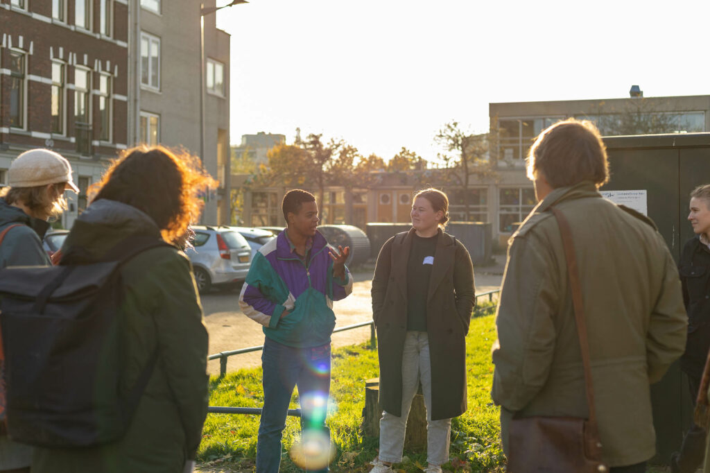 Groep mensen in gesprek op een zonnige dag in een stedelijke omgeving.