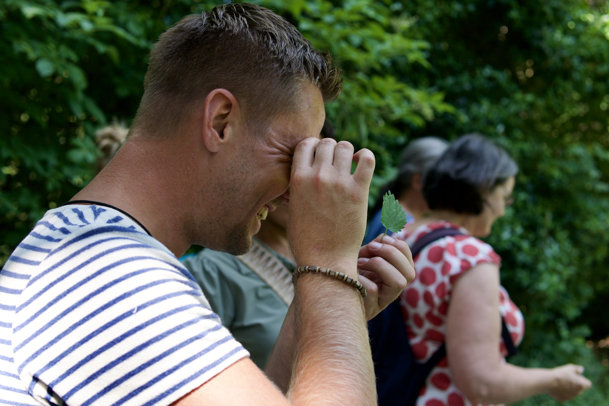 Een man onderzoekt een blad met een vergrootglas in een groene omgeving.