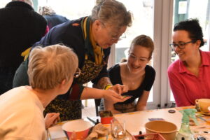 Groep mensen gezellig bezig met een creatieve workshop aan een tafel.