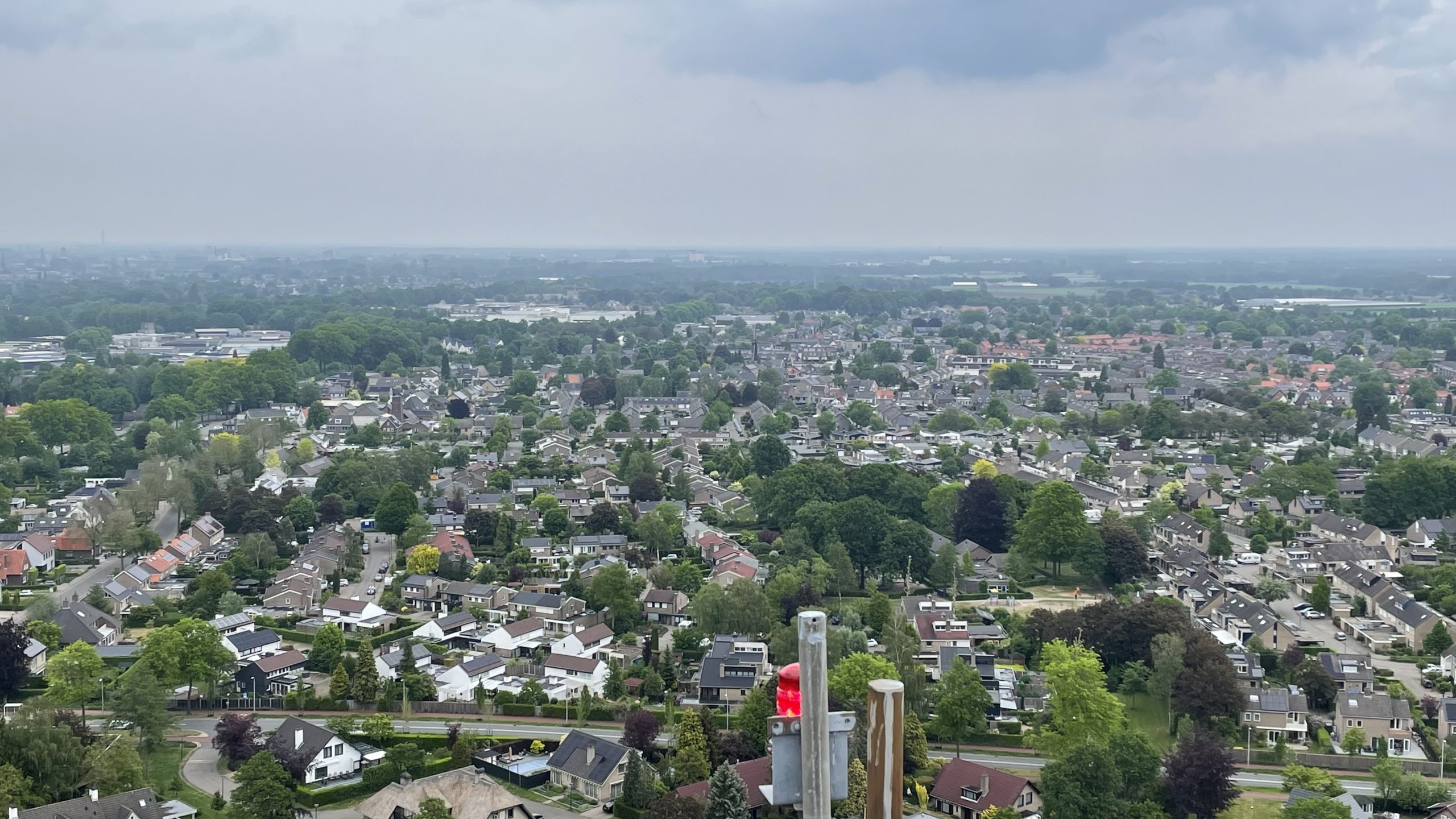 Luchtfoto van een groene woonwijk met veel laagbouwhuizen en een signaallicht op de voorgrond.