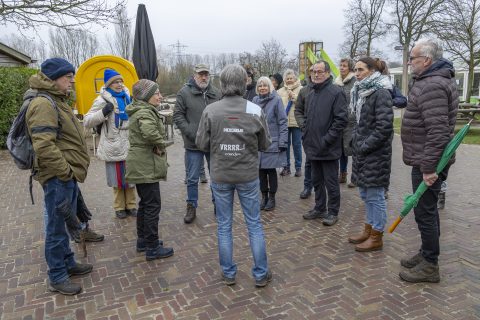 Een groep mensen staat in een kring buiten op een koude dag. Eén persoon draagt een jas met "DIERENRIJK".