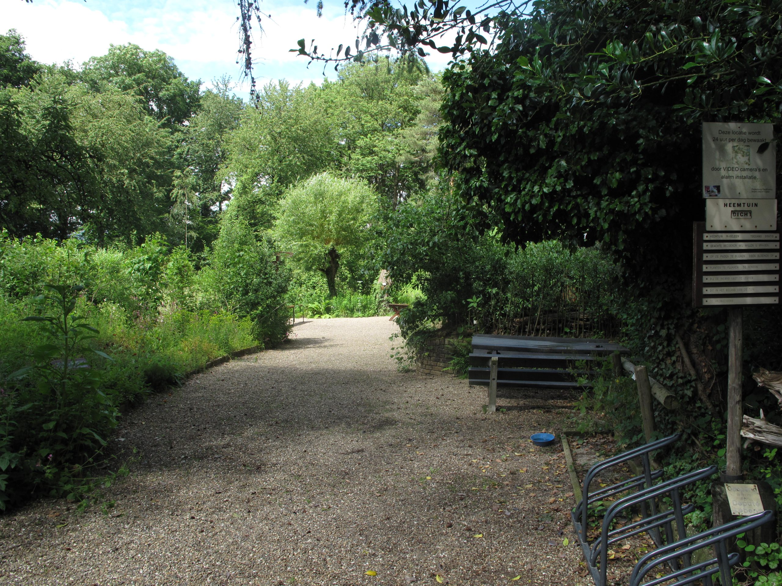 Grindpad in bosrijke omgeving met bankjes en een bord met tekst aan de rechterkant.
