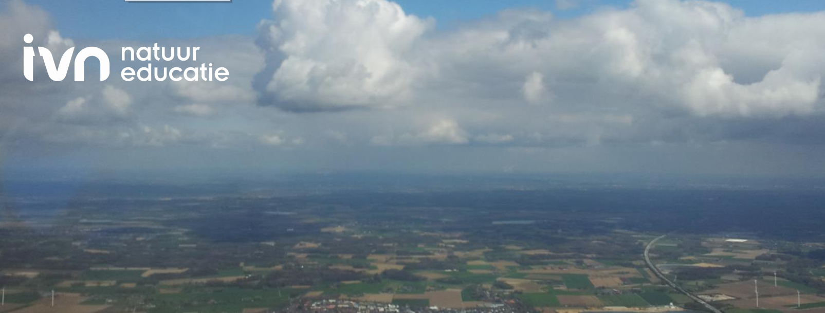 Landschap met velden en wegen onder een bewolkte lucht, logo 'IVN natuur educatie' bovenin.
