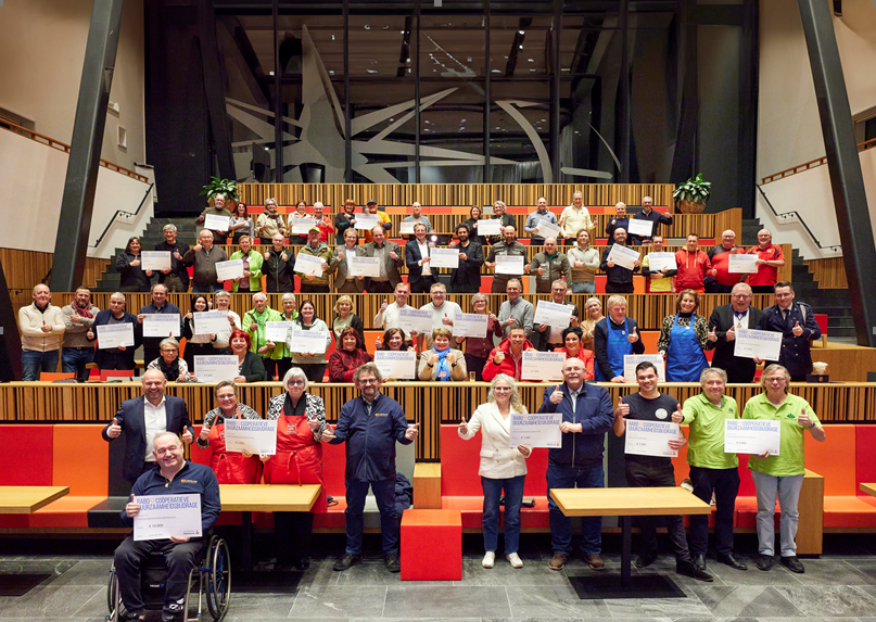 Groep mensen poseren met certificaten op tribune in moderne zaal.