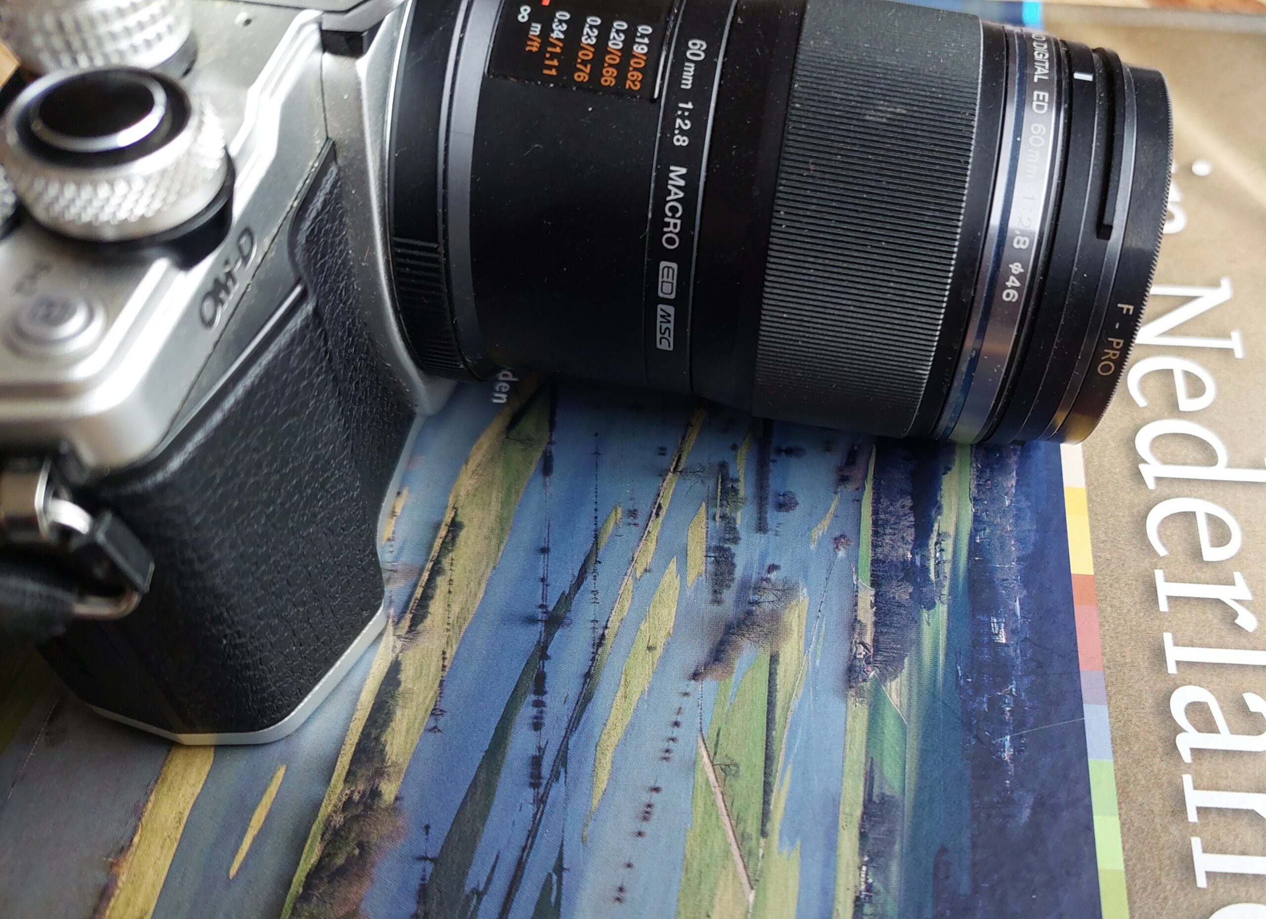 Camera met macrolens ligt op een boek met Nederlandse landschapsfoto.
