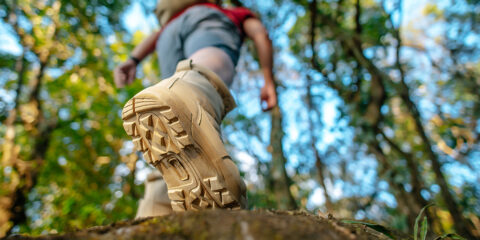 Close-up van een wandelaar in beige laarzen, stappend door een bos.
