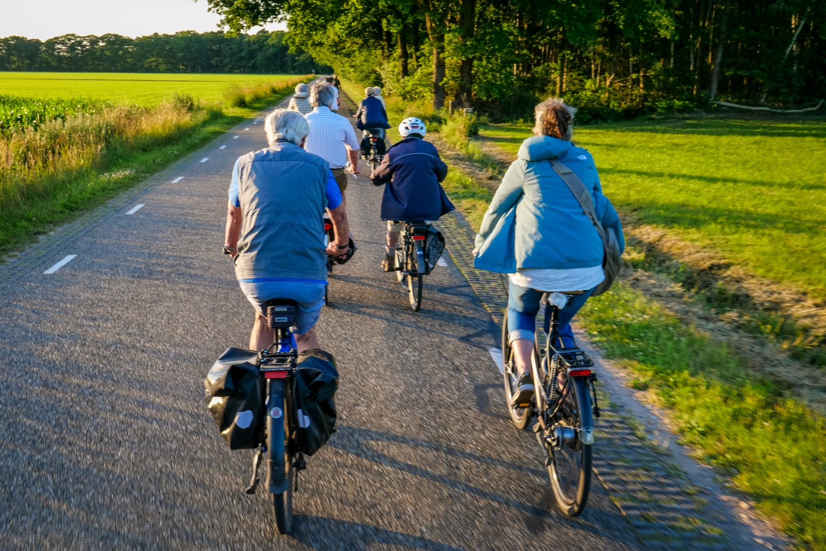 Groep mensen fietst op een landweg omgeven door groen.