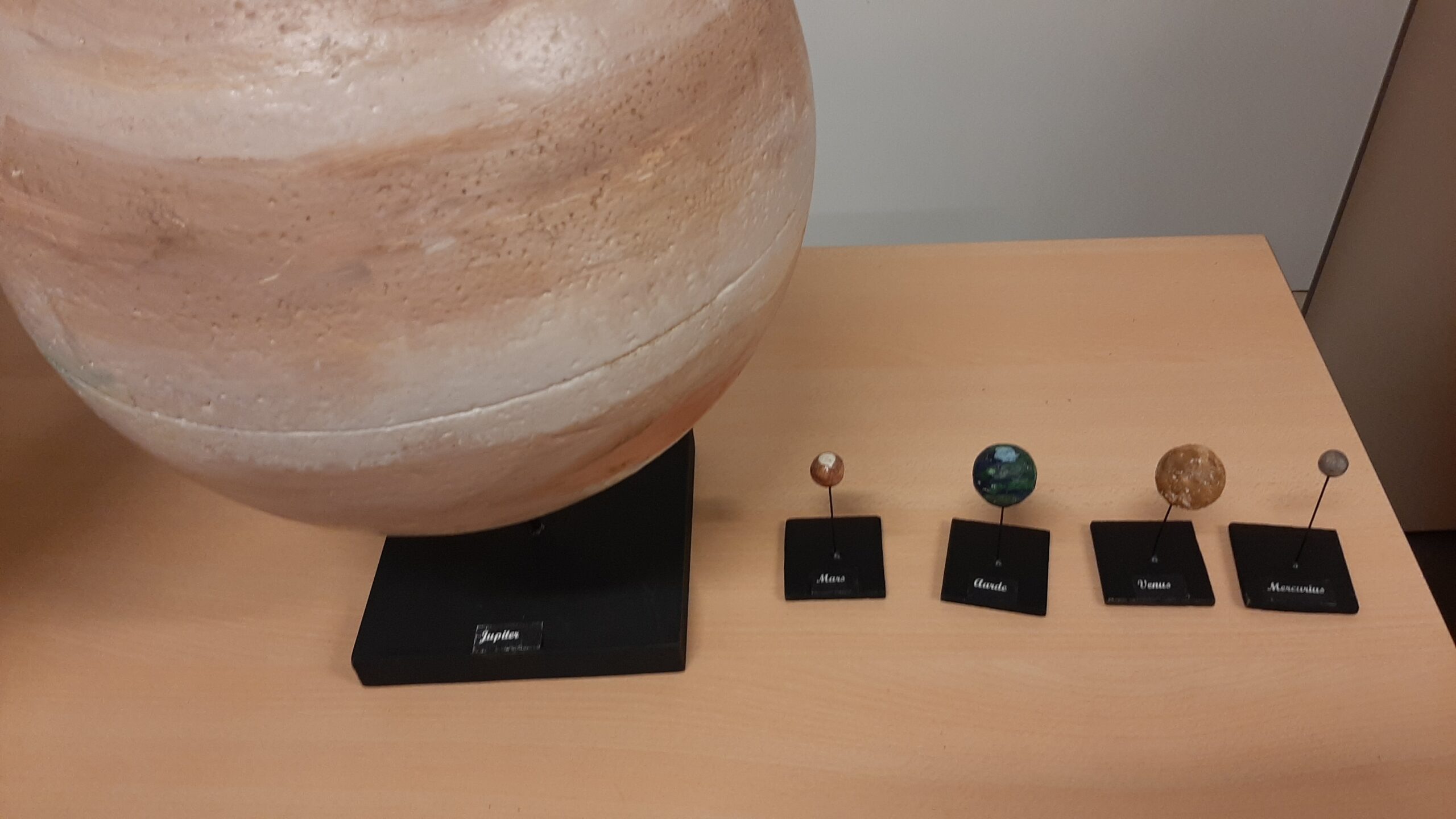 Model van planeten op een tafel, van links naar rechts: Jupiter, Mars, Aarde, Venus, Mercurius.