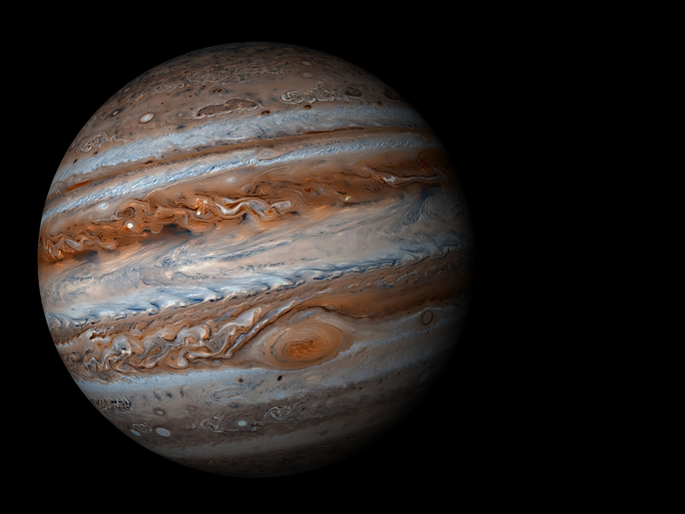 Gasplaneet Jupiter met kleurrijke wolkenbanden en Grote Rode Vlek zichtbaar op een zwarte achtergrond.