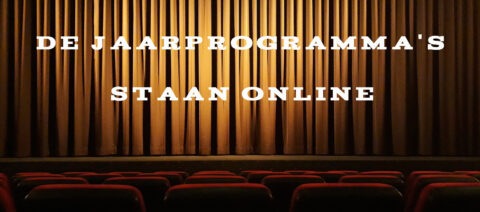 Goudkleurig theatergordijn met tekst: "De jaarprogramma's staan online," boven lege theaterstoelen.