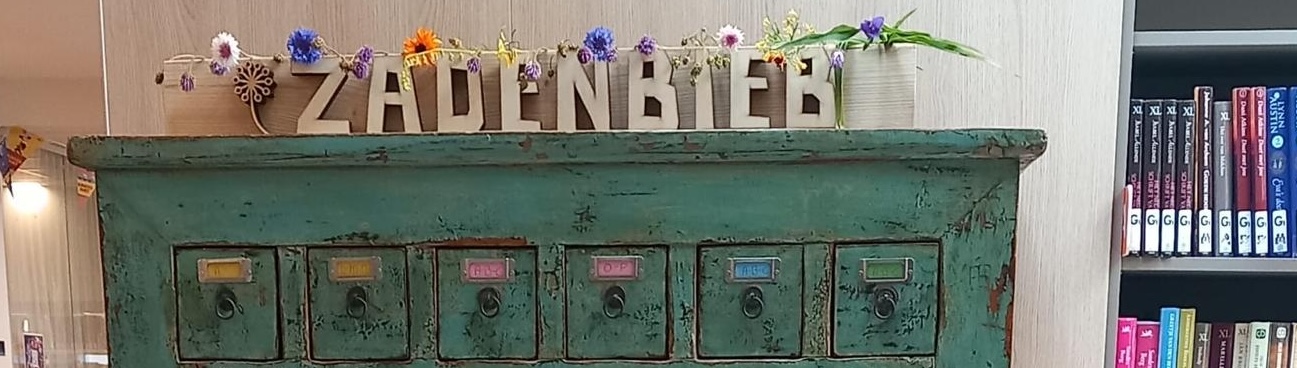 Groene kast met lade, versierd met bloemen en letters die "ZADENBIEB" vormen, naast boekenplank.