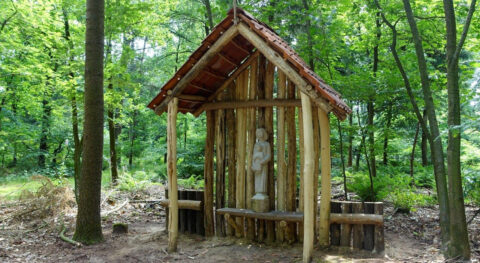 Houten kapel in bos met beeld van Maria en kind onder dak.