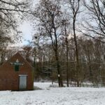 Bakstenen gebouw met "Dr Sliembergs" erop, in een besneeuwd boslandschap met kale bomen.