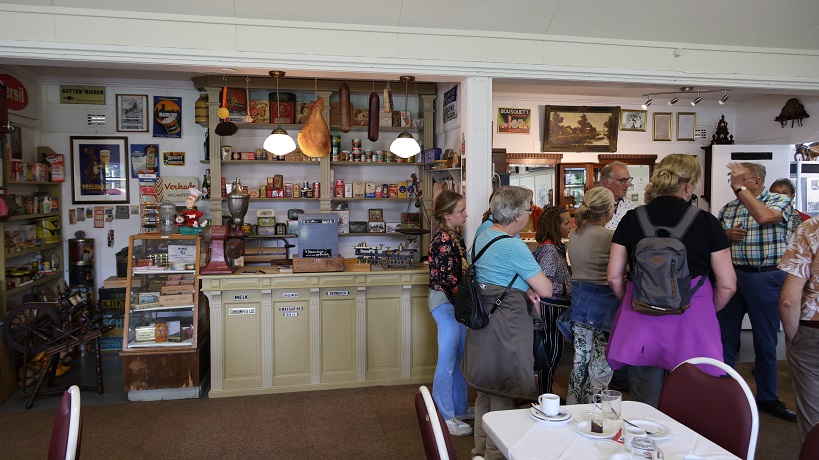 Groep mensen in een vintage winkel met retro producten en decoraties aan de muur.