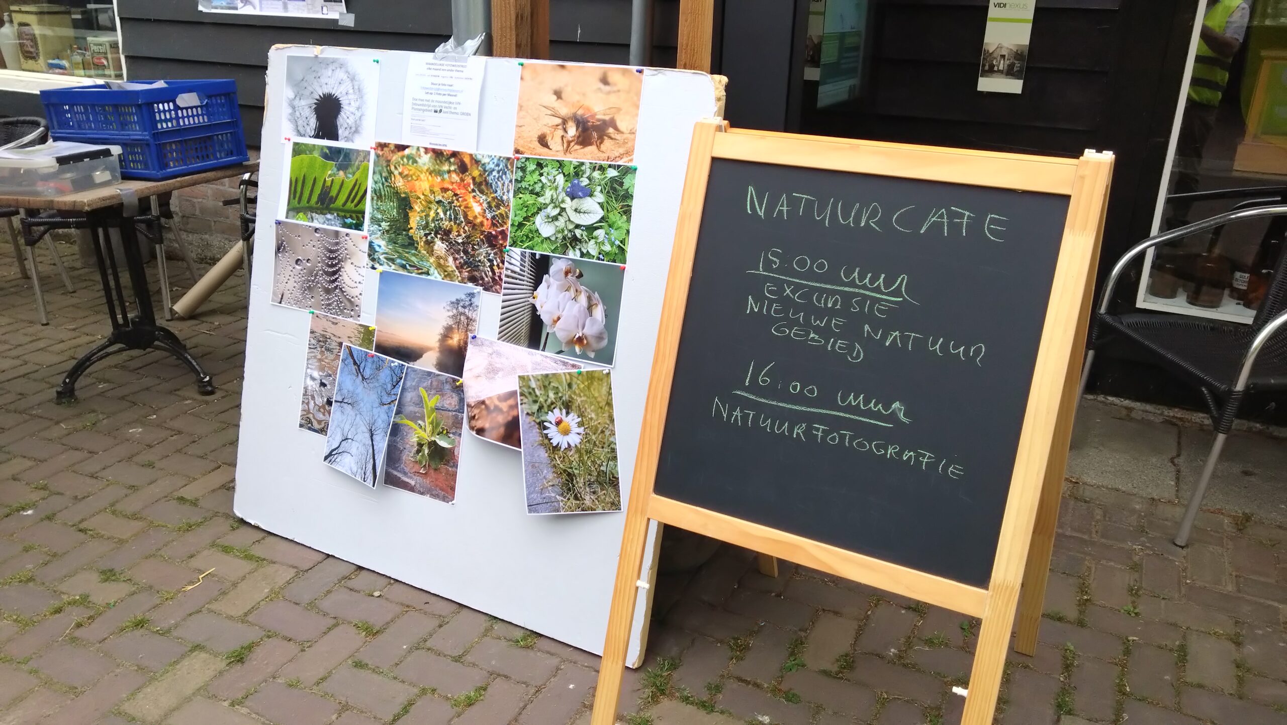Bord met natuurfoto's en krijtbord met activiteiten bij een natuurcafé, waaronder excursies.