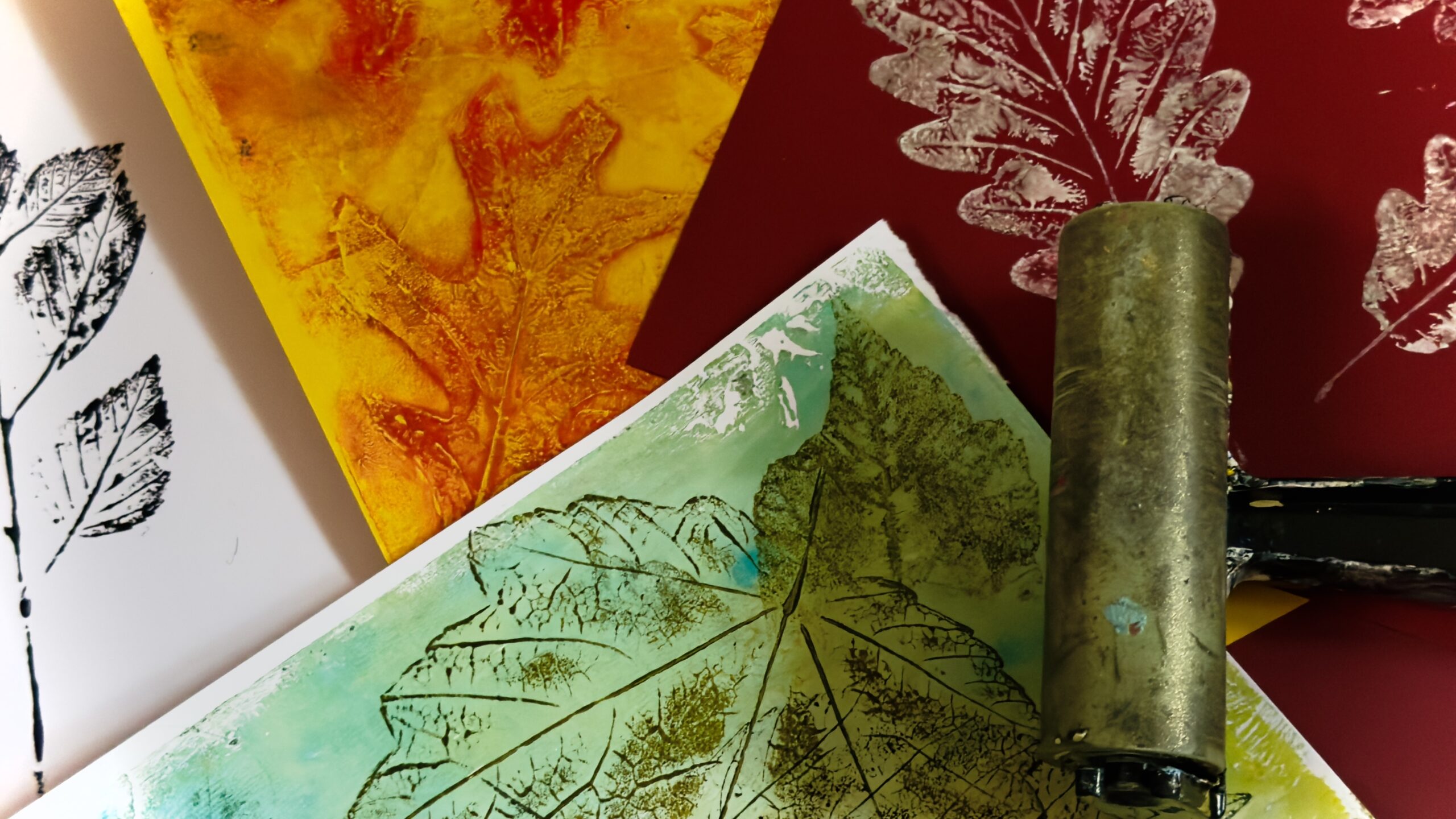 Afdrukken van bladeren in diverse kleuren met een verfroller op de voorgrond.