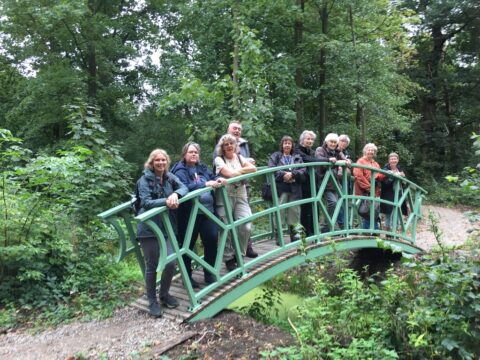 Groep mensen op een groene brug in een bosrijke omgeving.