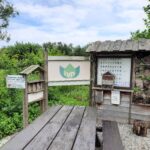 Houten informatiebord en insectenhotel in groene tuinomgeving; IVN-logo zichtbaar.