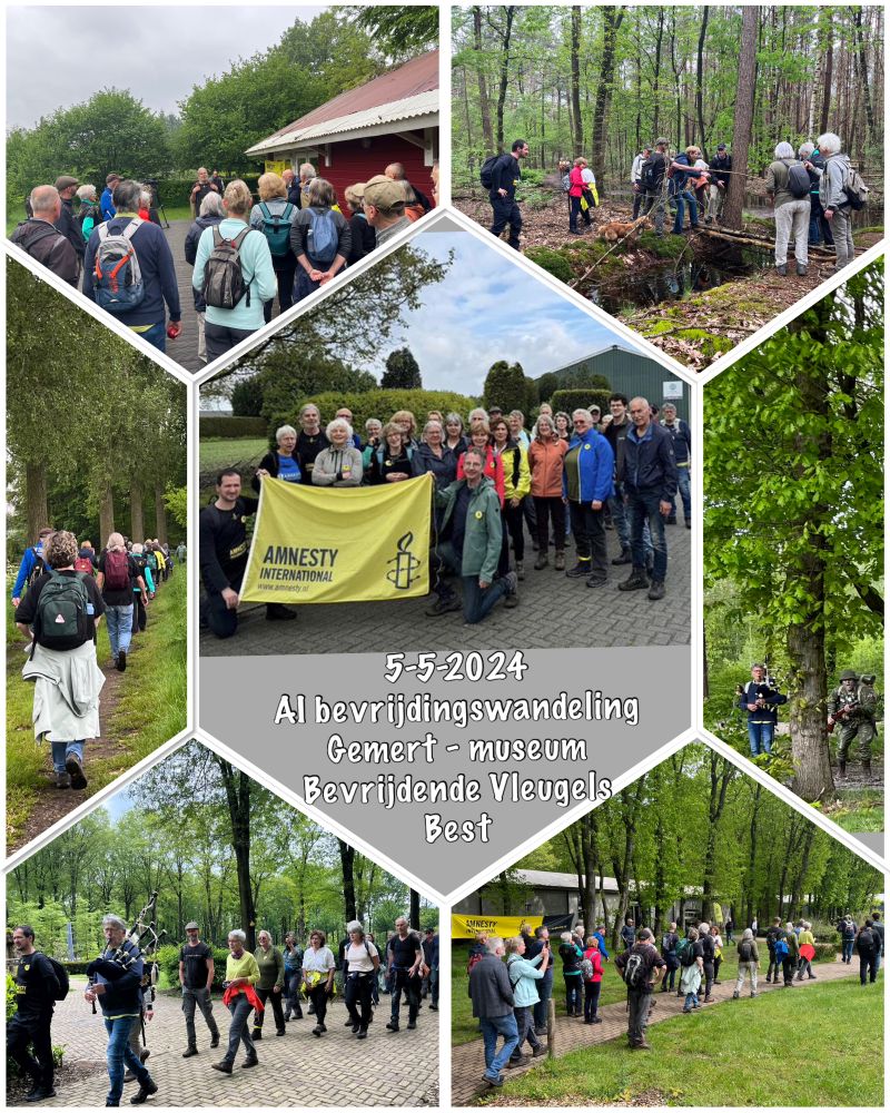 Groep mensen tijdens een bevrijdingswandeling door een bos en bij een museum, Amnesty-spandoek zichtbaar.