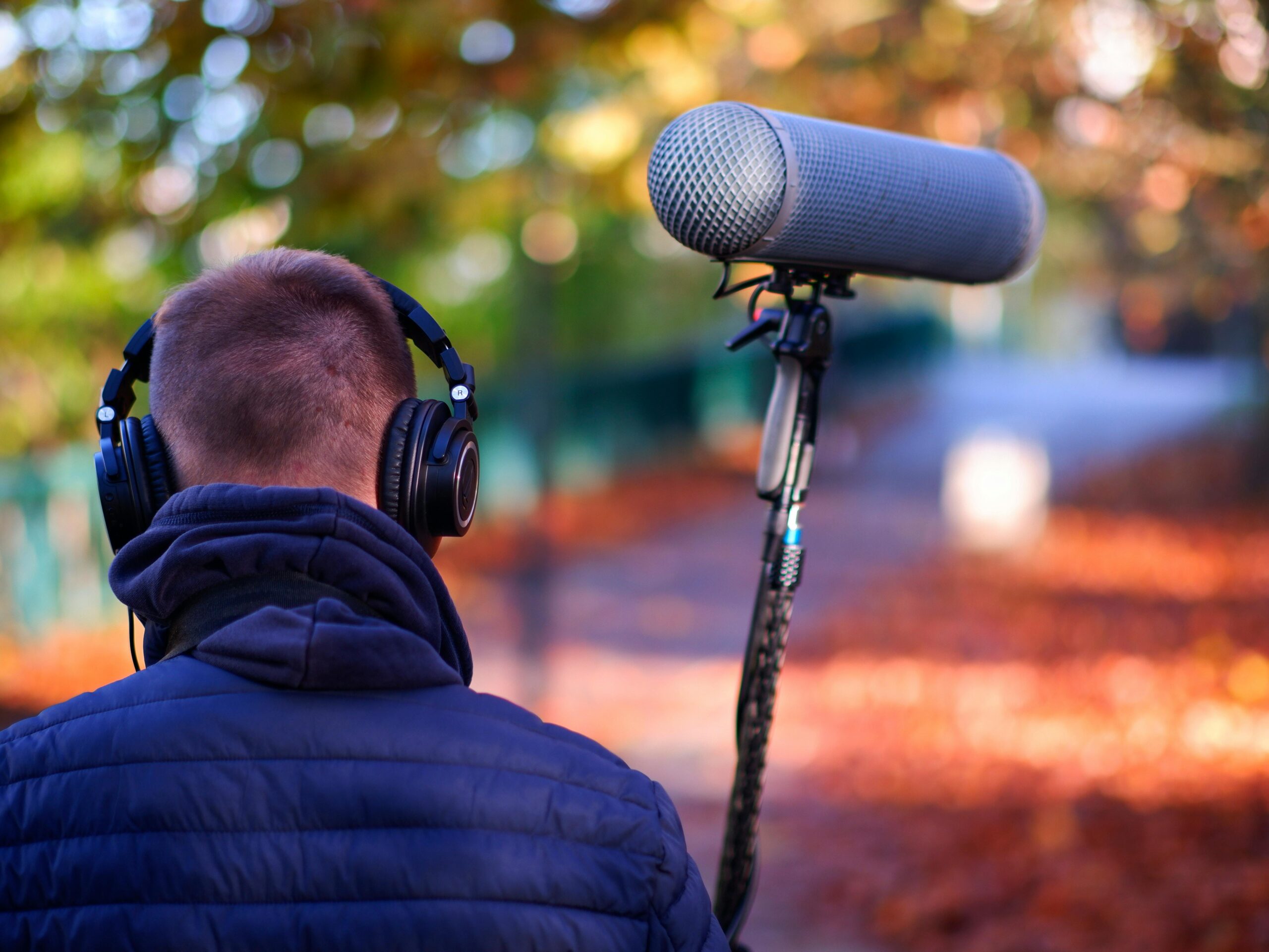 Man met koptelefoon en richtmicrofoon in herfstbos.