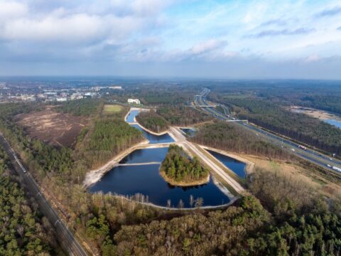 Luchtfoto van een weg met kruisingen omgeven door bos en water in een landelijke omgeving.